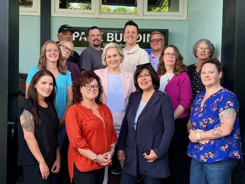 The Grand Management Services team, thirteen people, on the front steps of the Park Building at 375 Park Avenue in Coos Bay