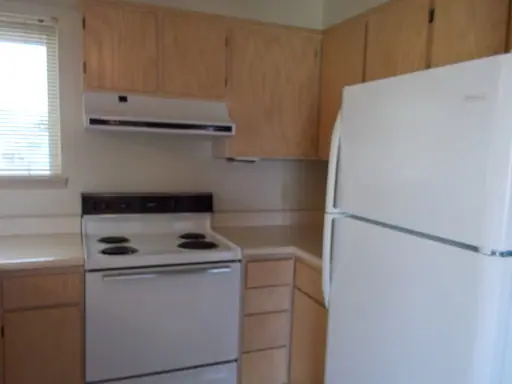 Kitchen with wood cabinets, an electric range and a refrigerator