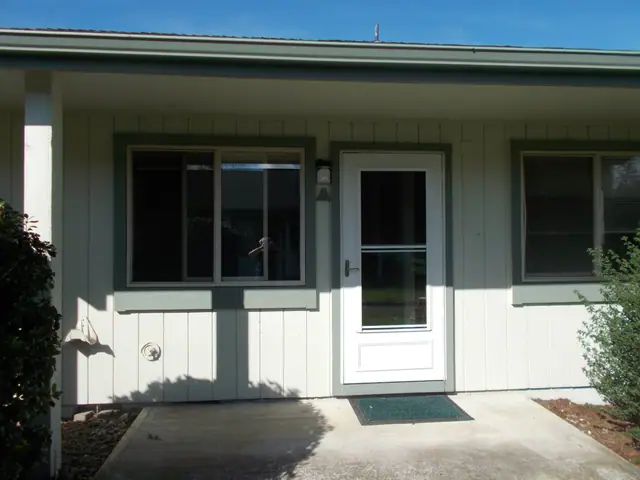Apartment entry with a covered porch, a glass storm door and two windows