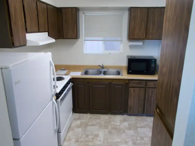 Kitchen with dark wood cabinets, a double sink and a microwave