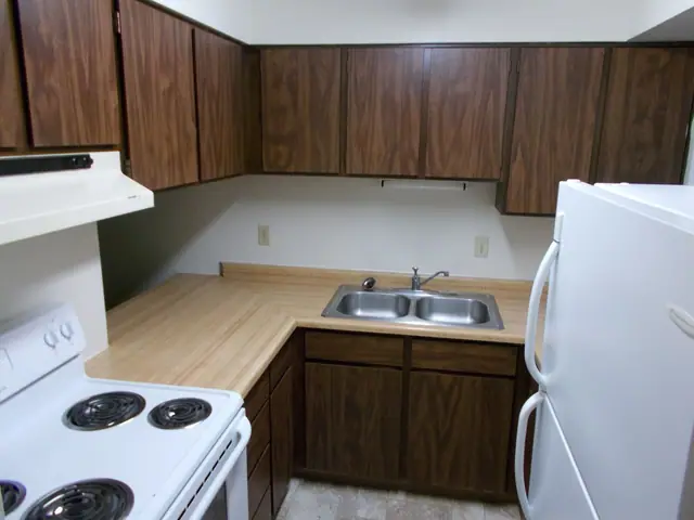 Kitchen with dark wood cabinets, a double sink and an electric range