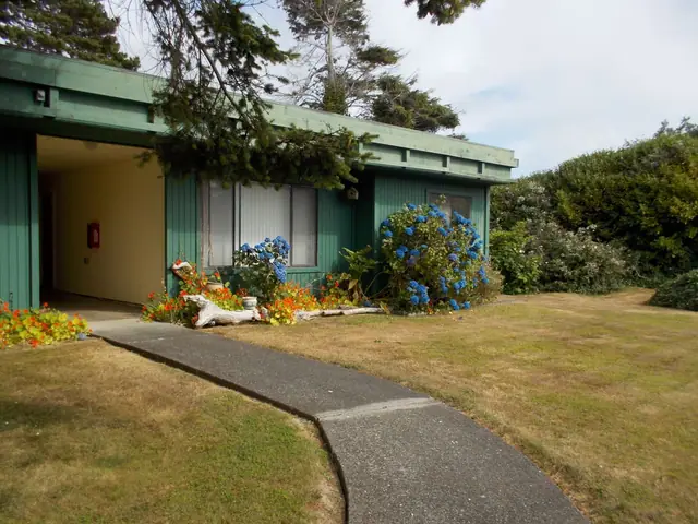 Green single-story building with blue hydrangeas by a walkway