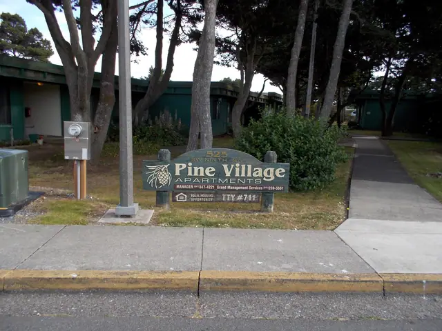 Pine Village Apartments sign by the sidewalk