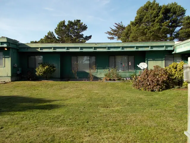 Green single-story building behind a wide lawn