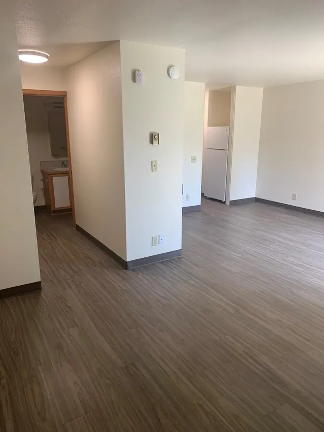 Hall to the bathroom beside the open dining area, with the refrigerator beyond