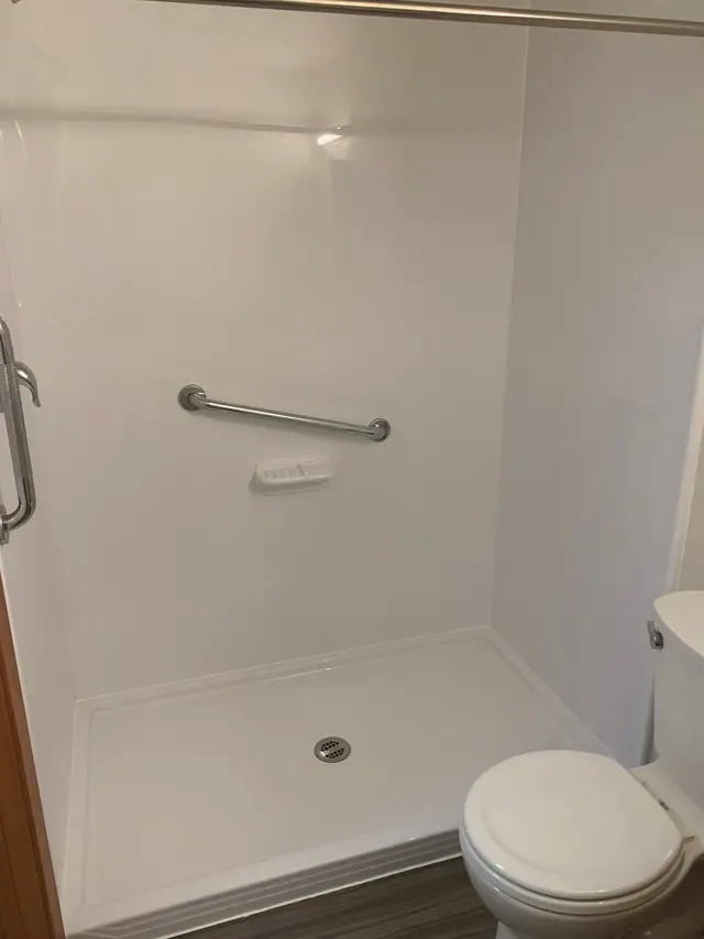 Shower with a grab bar, beside the toilet