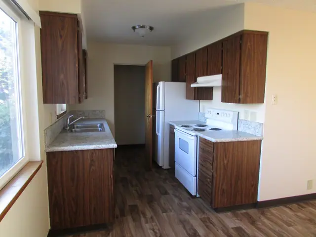 Galley kitchen with dark wood cabinets and a refrigerator