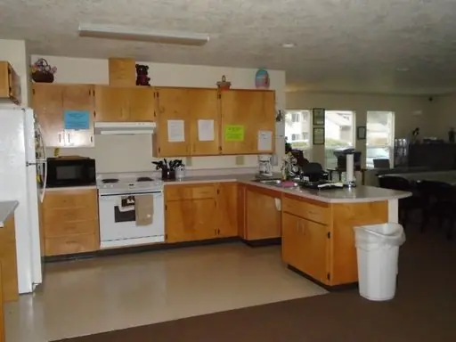 Community room kitchen with a range, a refrigerator and wood cabinets