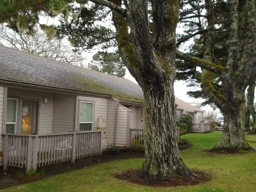 Single-story buildings with fenced patios under large trees
