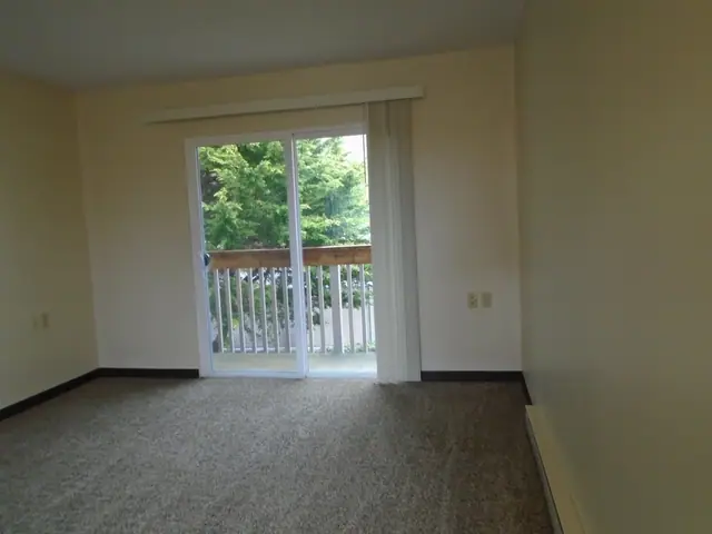 Living room with carpet and a sliding door to a balcony