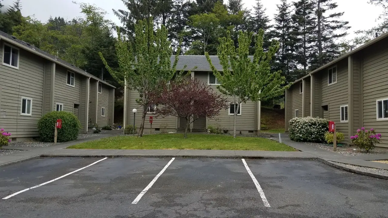 Parking lot facing two-story buildings and flowering trees