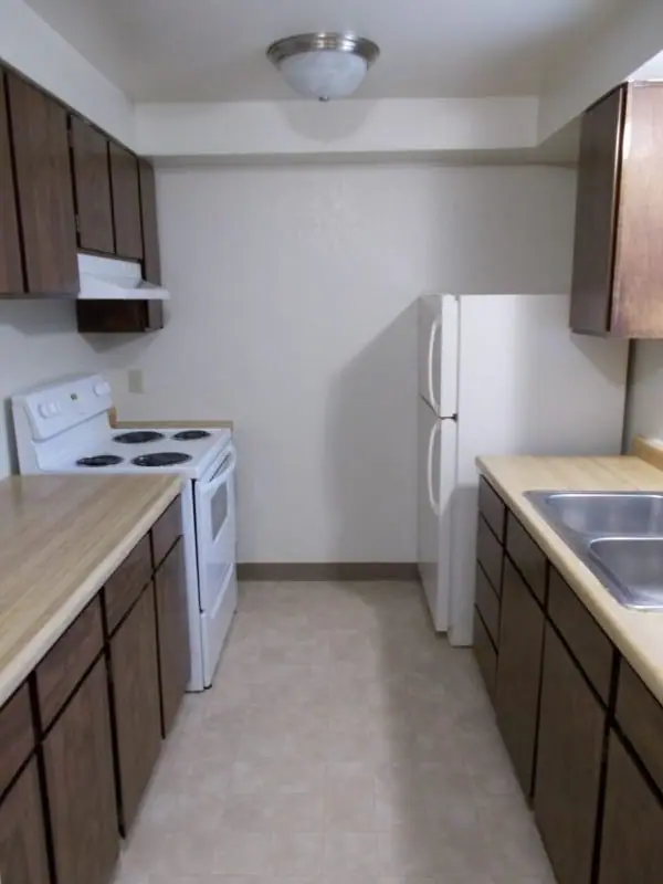 Galley kitchen with dark wood cabinets and a refrigerator