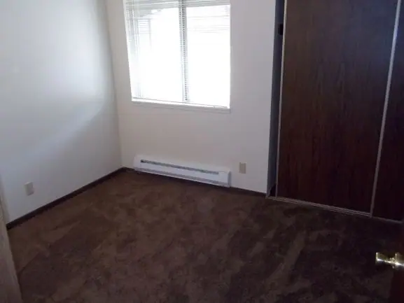 Empty bedroom with a window and a sliding closet door