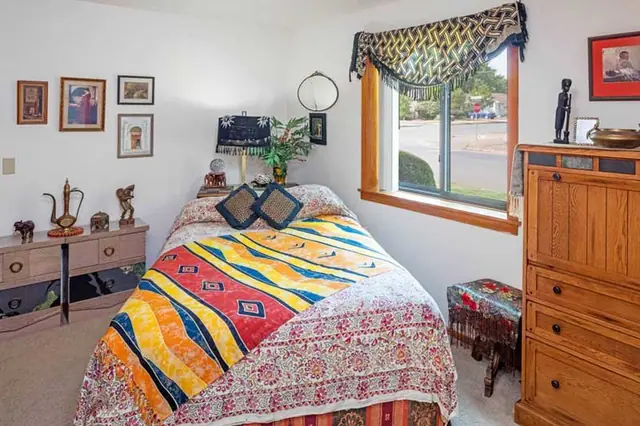 Bedroom with a bright quilt and a wood dresser