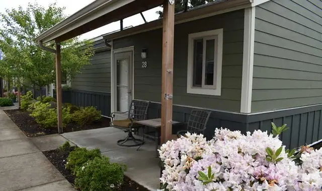 Covered patio with a table and chairs by an apartment door