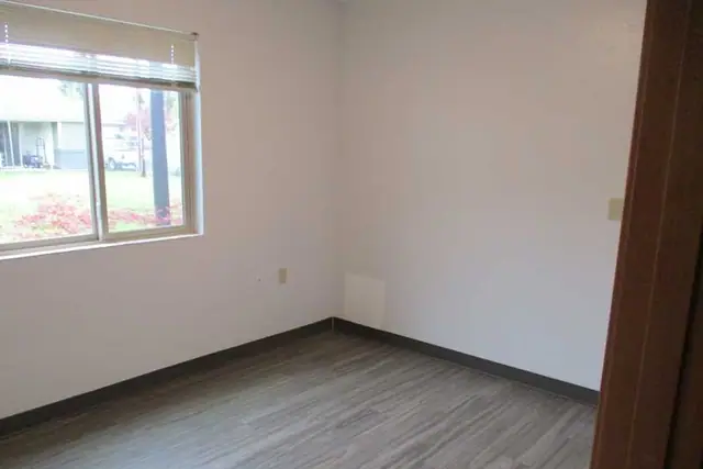 Empty bedroom with wood-look flooring and a window
